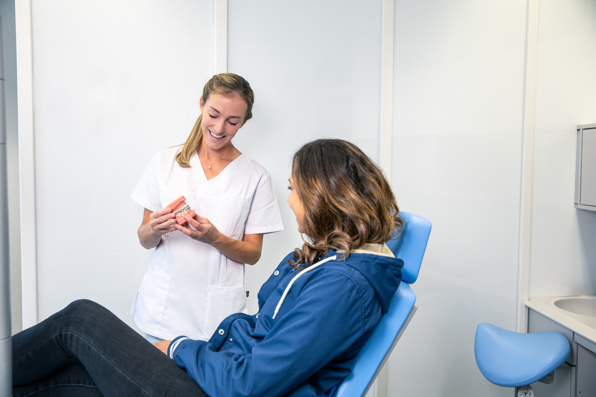Kieferorthopädin zeigt ein Zahnmodell mit Brackets